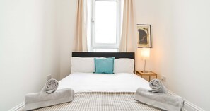 A hotel room with a bed, a window with curtains, a bedside lamp, and a framed picture on the wall. - Modern Central Apartment (Aberdeen)
