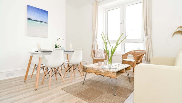 A modern living room with a dining area, featuring a wooden coffee table, white chairs, and a wicker sofa. - Modern Central Apartment (Aberdeen)