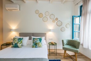A bedroom with a bed, a green armchair, a small table, and wall decor. - Daria's Home (Rethymno)