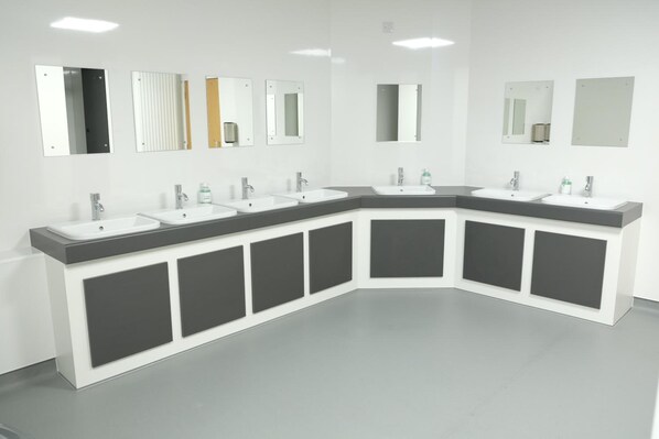 A modern bathroom with a curved vanity, multiple sinks, and mirrors.