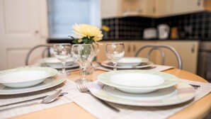 A dining table set with plates, glasses, and cutlery, with a vase of yellow flowers in the center.