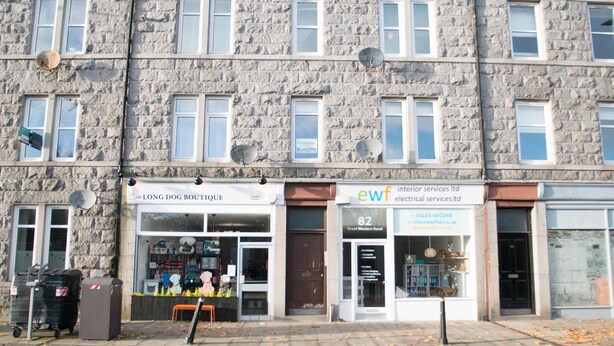 A stone building with multiple storefronts, including a boutique and an electrical services company.