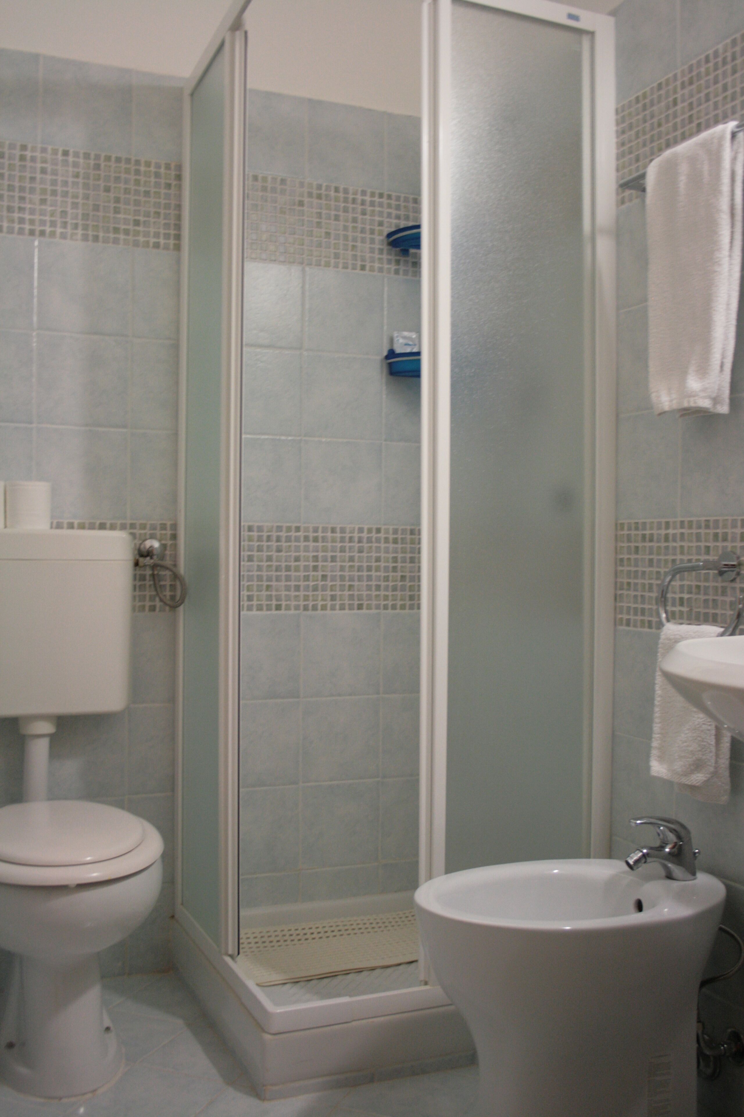 Un baño con inodoro, cabina de ducha y lavamanos.