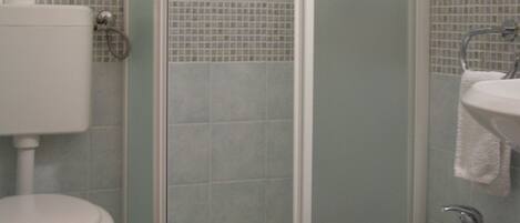 Un baño con inodoro, cabina de ducha y lavamanos.