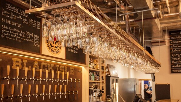 A bar area with multiple beer taps and a selection of glasses hanging from the ceiling. - Black Isle Bar and Rooms (Inverness)