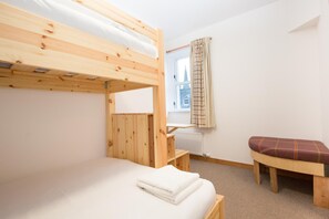 A bunk bed room with a window, a radiator, and a bench.