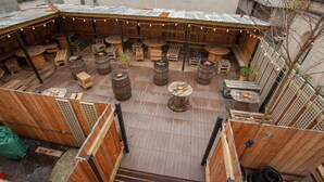 An outdoor seating area with wooden tables and barrels, surrounded by wooden fences and a corrugated metal roof. - Black Isle Bar and Rooms (Inverness)