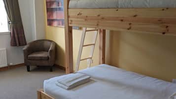 Una cama litera con una escalera, una silla y un radiador en una habitación con paredes amarillas.