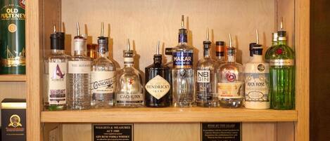 A bar area with multiple shelves of liquor bottles, a bar counter with various bottles and a coffee machine.