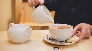 Una persona sirviendo té en una taza sobre una mesa de madera.