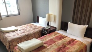 Habitación de hotel con dos camas, cada una con una colcha estampada, una lámpara de noche y un teléfono en la mesita.