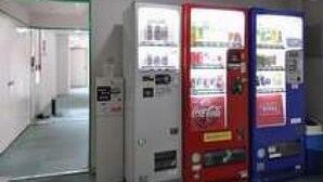A hallway with vending machines and a door with a green exit sign. - Green Hotel Shimonoseki (Shimonoseki)