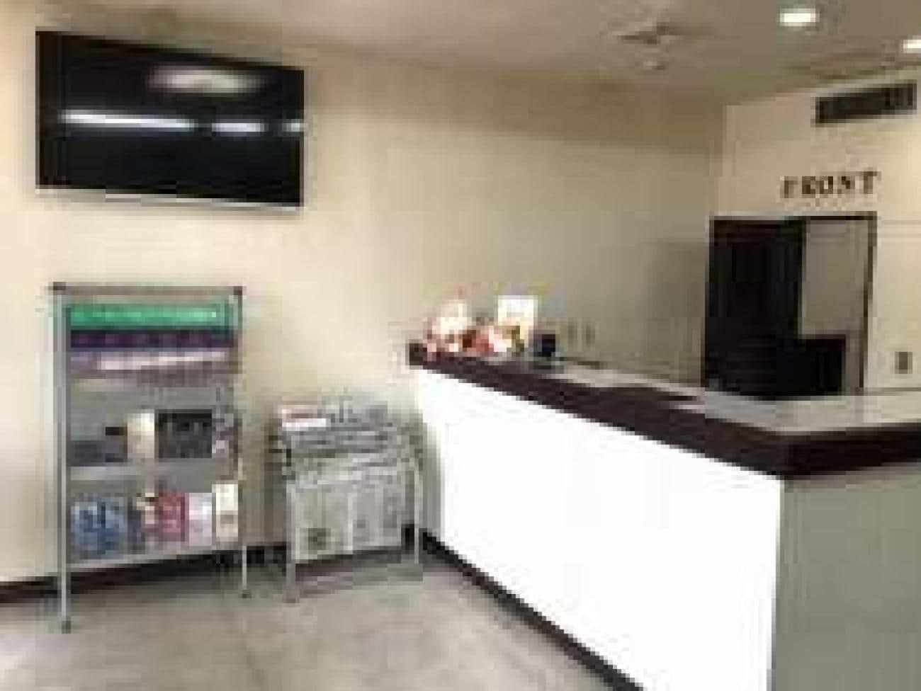 A reception area with a counter, a television mounted on the wall, and a shelf with magazines.