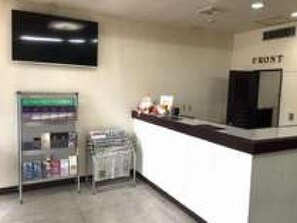 A reception area with a counter, a television mounted on the wall, and a shelf with magazines. - Green Hotel Shimonoseki (Shimonoseki)