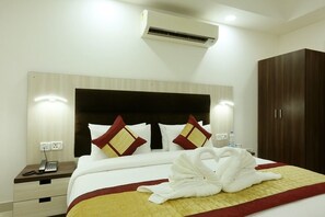 A hotel room with a bed, a bedside table with a phone, an air conditioner, and a wardrobe. - Green Lotus Residency (New Delhi)