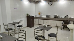A modern kitchen with a dining area, equipped with stainless steel appliances and a clock on the wall.