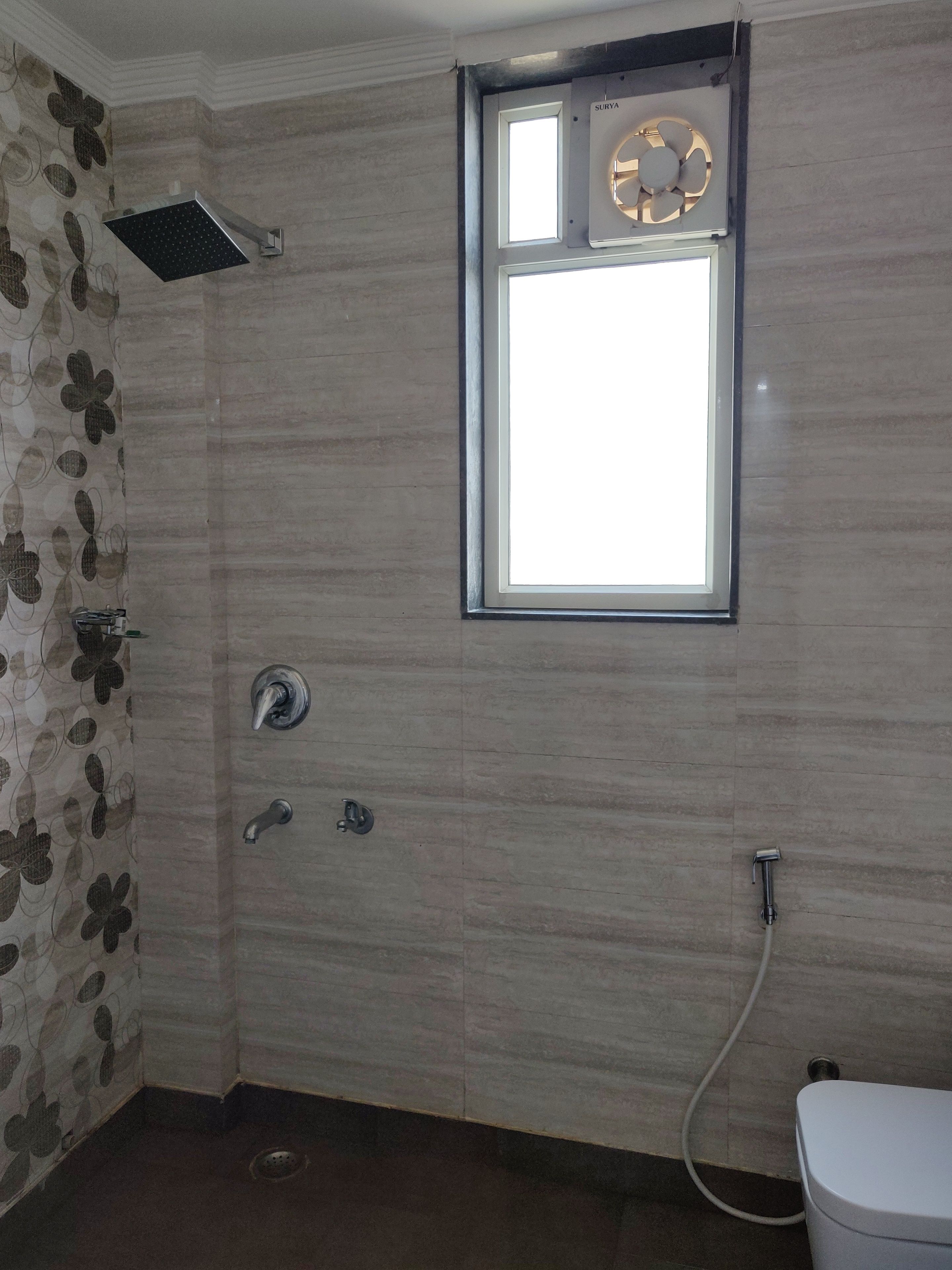 A bathroom with a shower, a window, and a toilet.