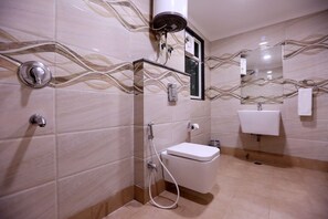 A bathroom with a toilet, sink, and shower. - Green Lotus Residency (New Delhi)