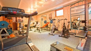 Ett gym med olika typer av träningsutrustning, inklusive löpband, styrketräningsmaskiner och fria vikter.