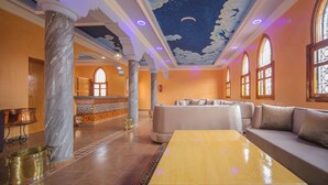 Un vestíbulo espacioso con una columna de mármol, un mostrador de recepción, un sofá y un techo decorado con un diseño de noche estrellada.
