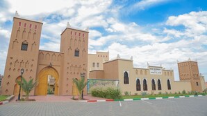 Un gran edificio con múltiples torres y entradas arqueadas, que muestra un letrero que dice "KSAH BEN YOUSSES".