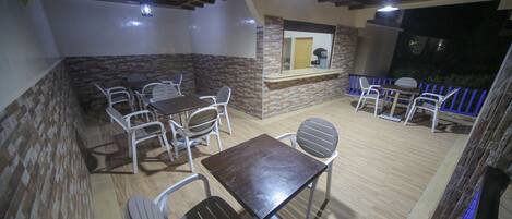 Un patio exterior con una mesa y sillas de madera, un muro de piedra y vistas al exterior.