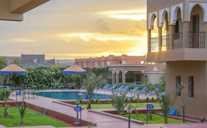 Una piscina al aire libre, sombrillas, sillones reclinables de piscina