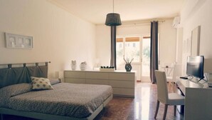 A bedroom with a bed, a desk, a chair, a television, and a window with curtains. - B&B La Peonia (Reggio Calabria)