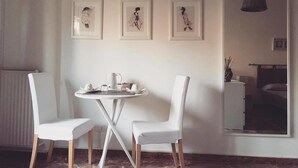 A room with a round table and two white chairs, a radiator, and three framed artworks on the wall. - B&B La Peonia (Reggio Calabria)