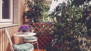 A wooden deck with a table and chairs, surrounded by dense foliage. - B&B La Peonia (Reggio Calabria)