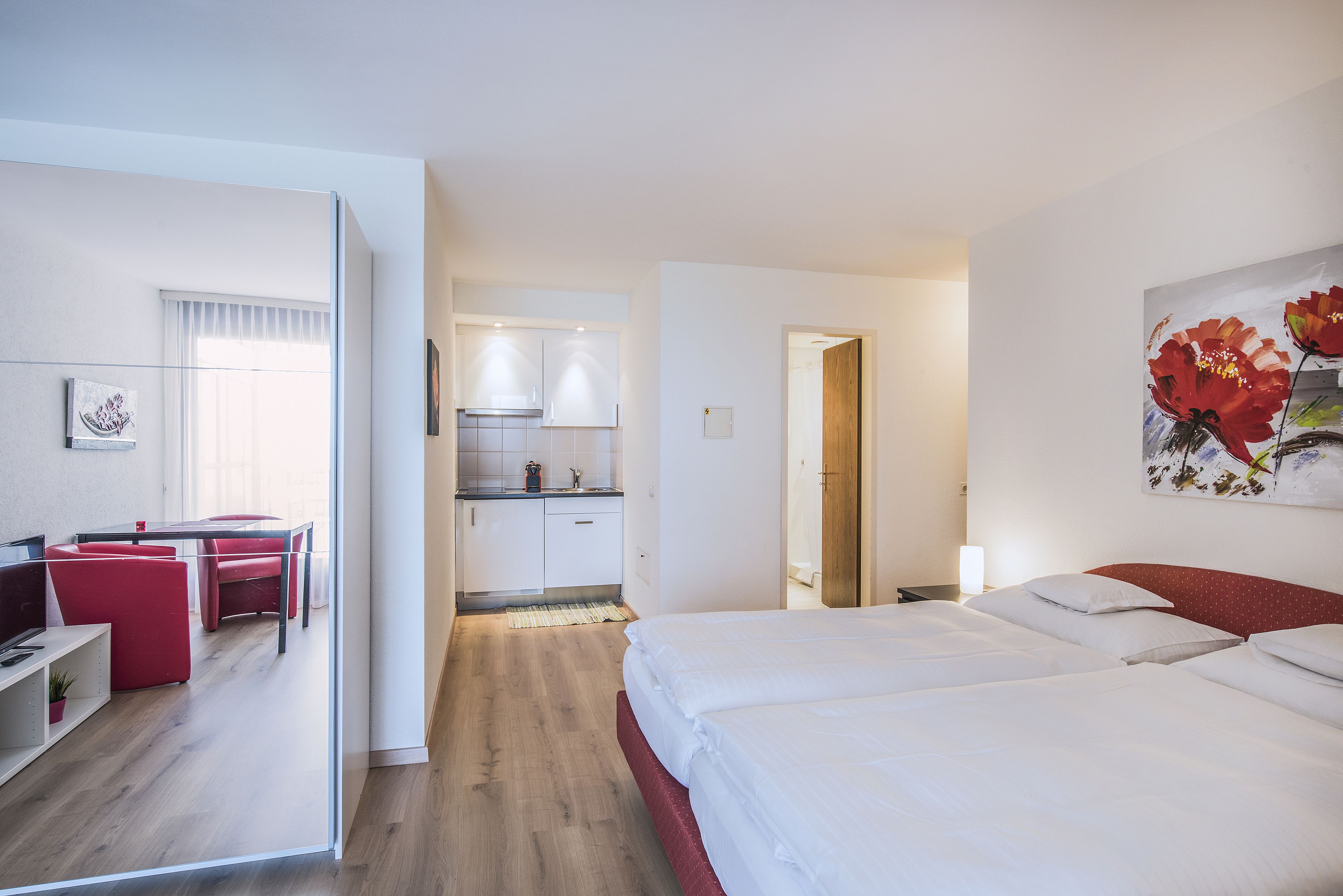 Et hotelværelse med seng, skrivebord og tekøkken.