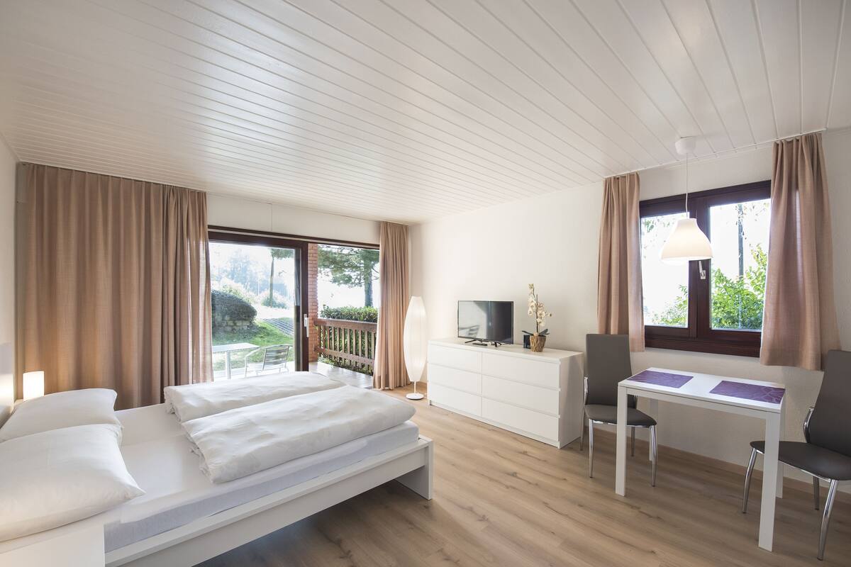 A modern hotel room with a bed, a desk, and a TV.