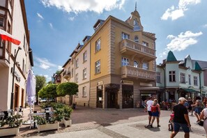 Une place avec des sièges en plein air, un immeuble doté d’un balcon et un magasin avec une enseigne.
