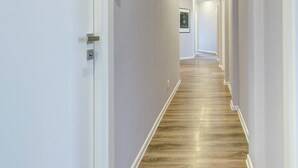 Un couloir aux murs blancs, au plancher en bois et doté d’un éclairage encastré.