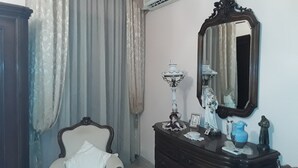 Una habitación con una silla, un aparador, un espejo y una ventana con cortinas.