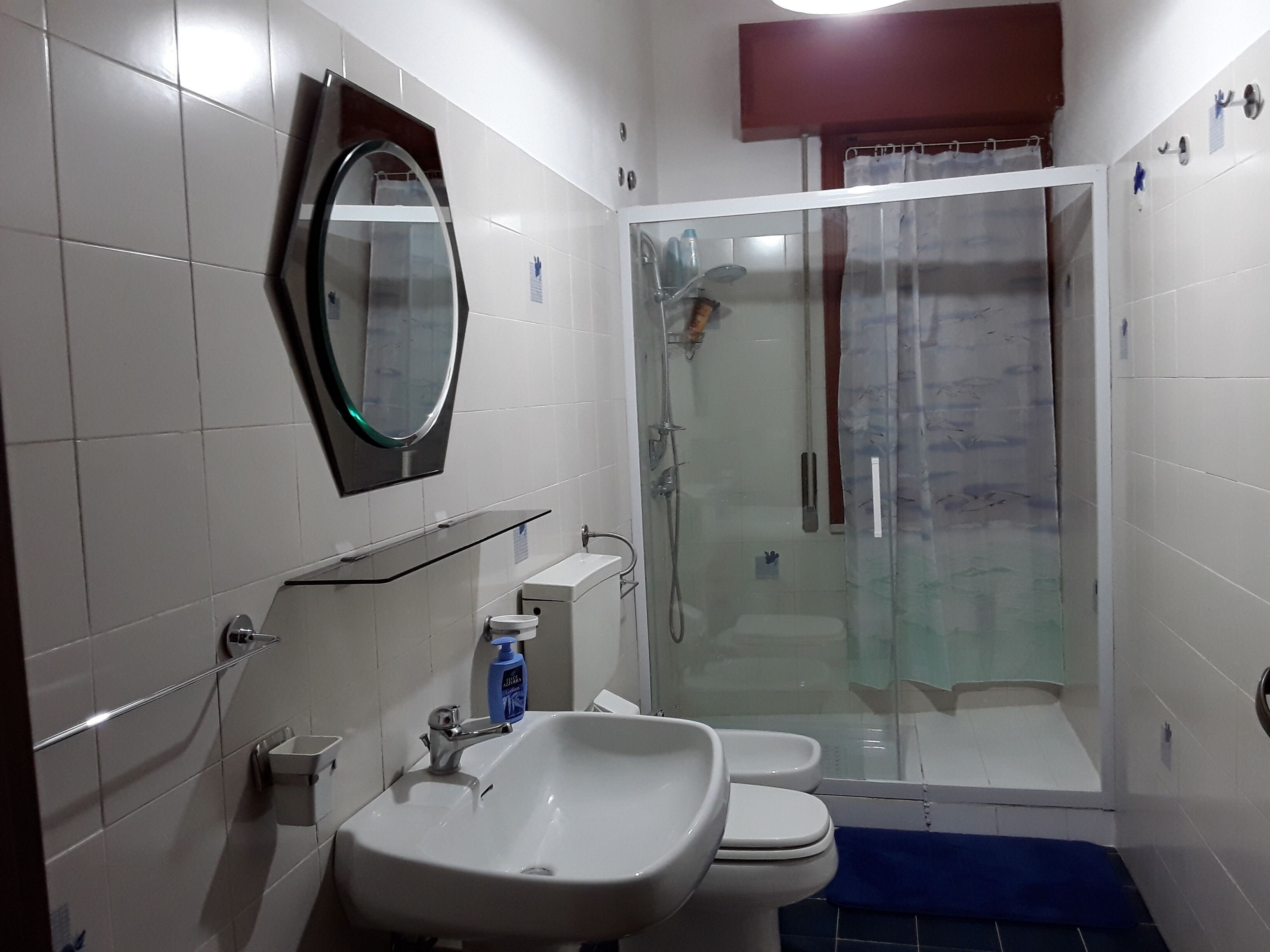 A bathroom with a glass-enclosed shower, a sink, and a toilet.