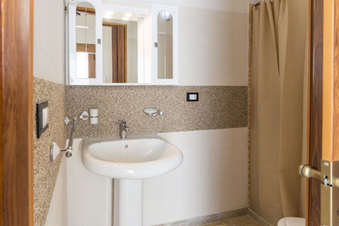 Un bagno con lavandino, specchio e tenda per la doccia.