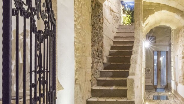 A narrow stone staircase leading to a door with a window, surrounded by stone walls and a metal gate. - Dimora Corte Antica Scorrano (Scorrano)