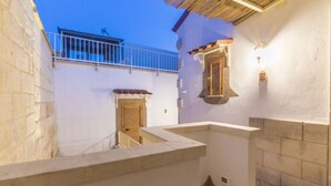 A narrow outdoor corridor with a stone bench, a wooden door, and a small balcony with a railing. - Dimora Corte Antica Scorrano (Scorrano)