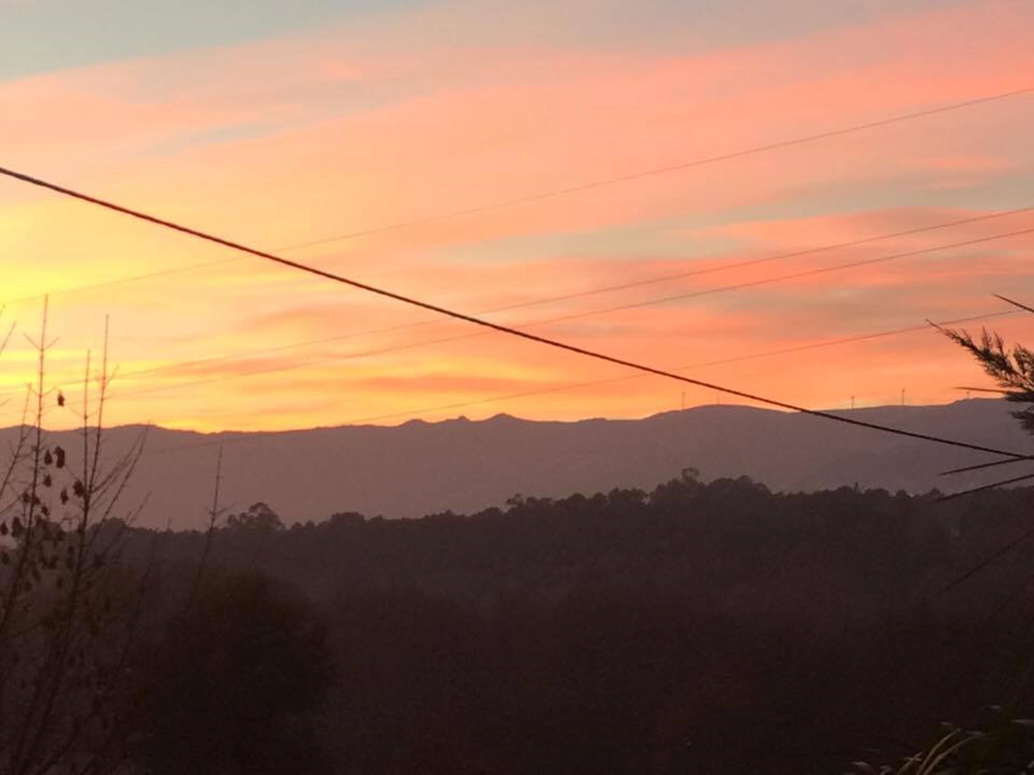 A sunset view with power lines across the sky.