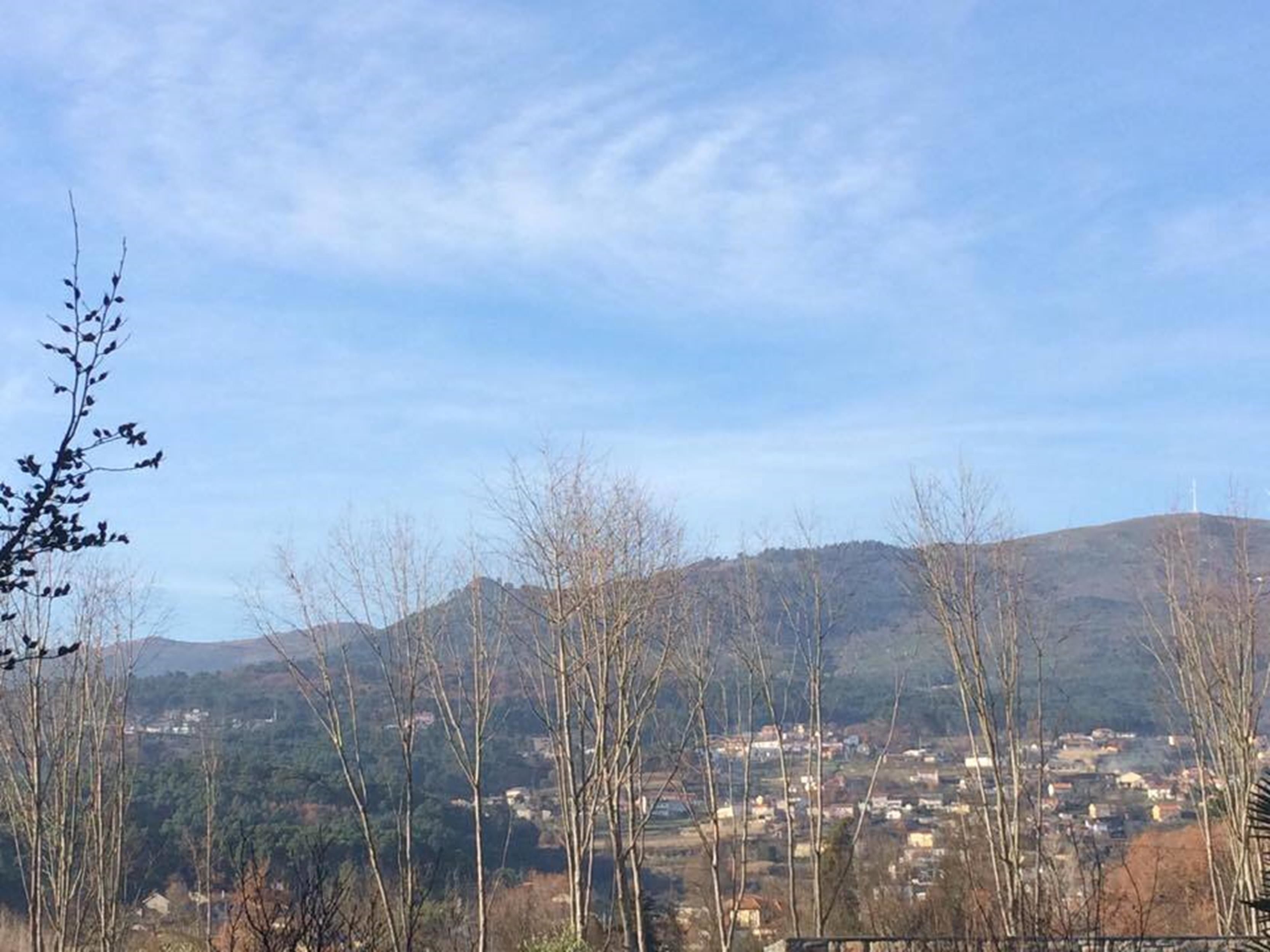 A view of a town with houses and trees in the foreground, and hills in the background.