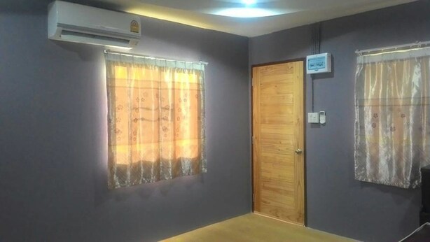 A room with two windows with floral curtains, a wooden door, and an air conditioning unit mounted on the wall. - SiBamboo 2 (Chiang Rai)