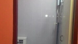 A small, enclosed bathroom with a toilet, a shower, and a tiled floor. - SiBamboo 2 (Chiang Rai)