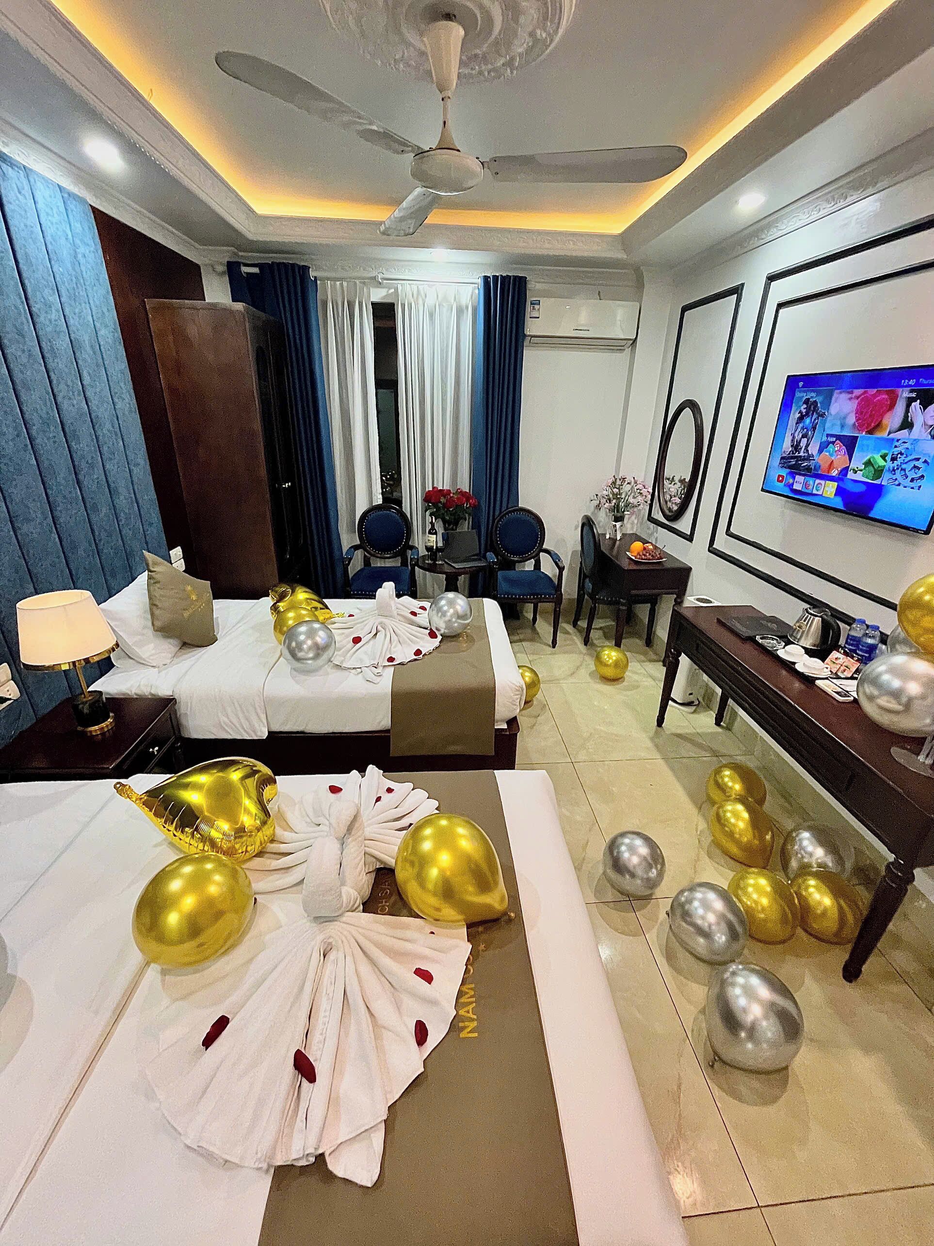 A hotel room with two beds, a TV, a desk, and a ceiling fan.
