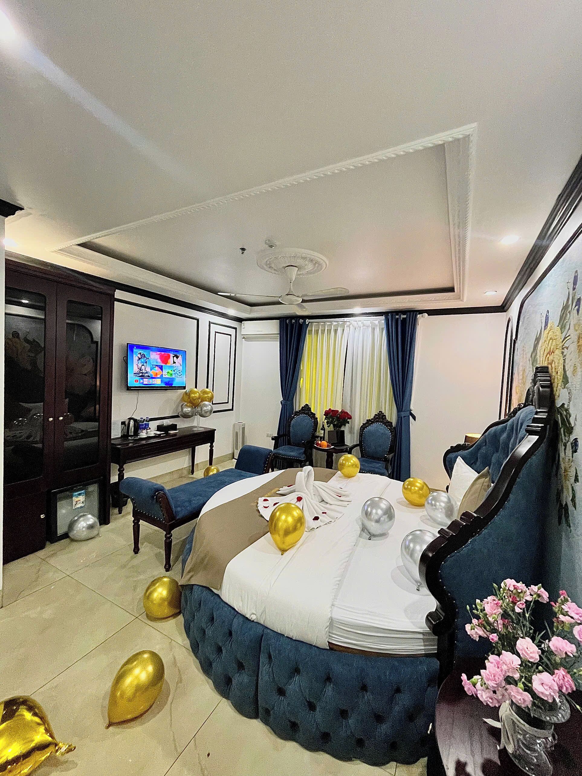 A hotel room with a large bed, a television, a desk, and a chair.