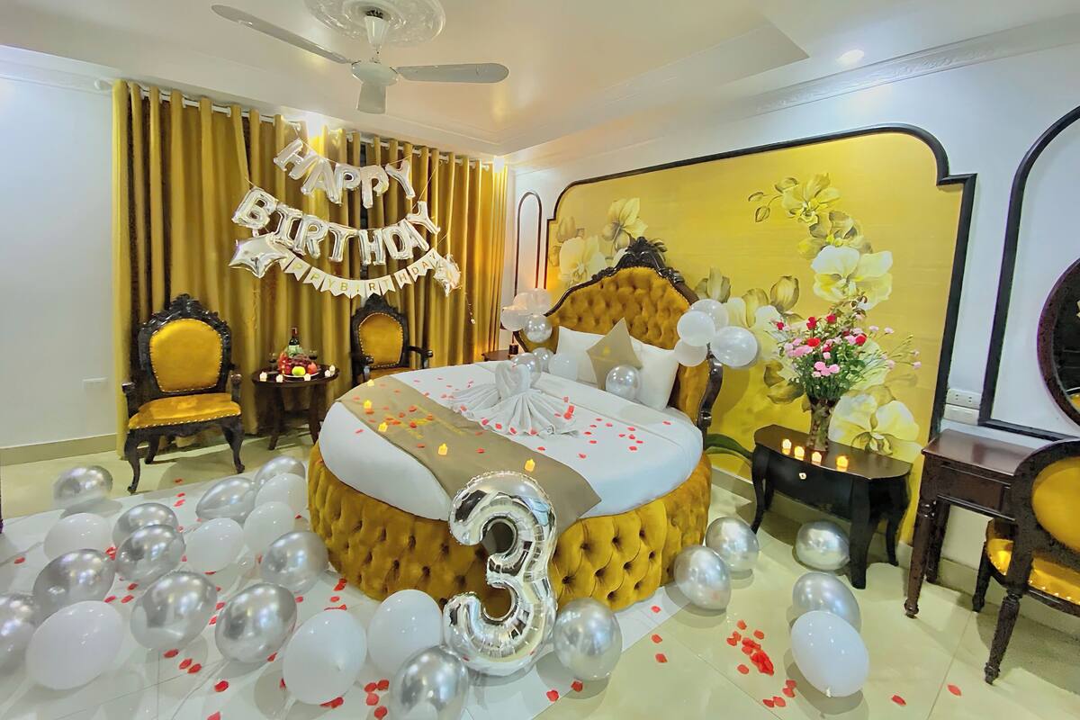 Une chambre à coucher luxueuse, dotée d’une tête de lit capitonnée, d’un grand lit et d’un ventilateur de plafond.