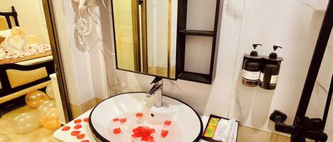 Un baño con un lavamanos redondo, un secador de pelo y un espejo.