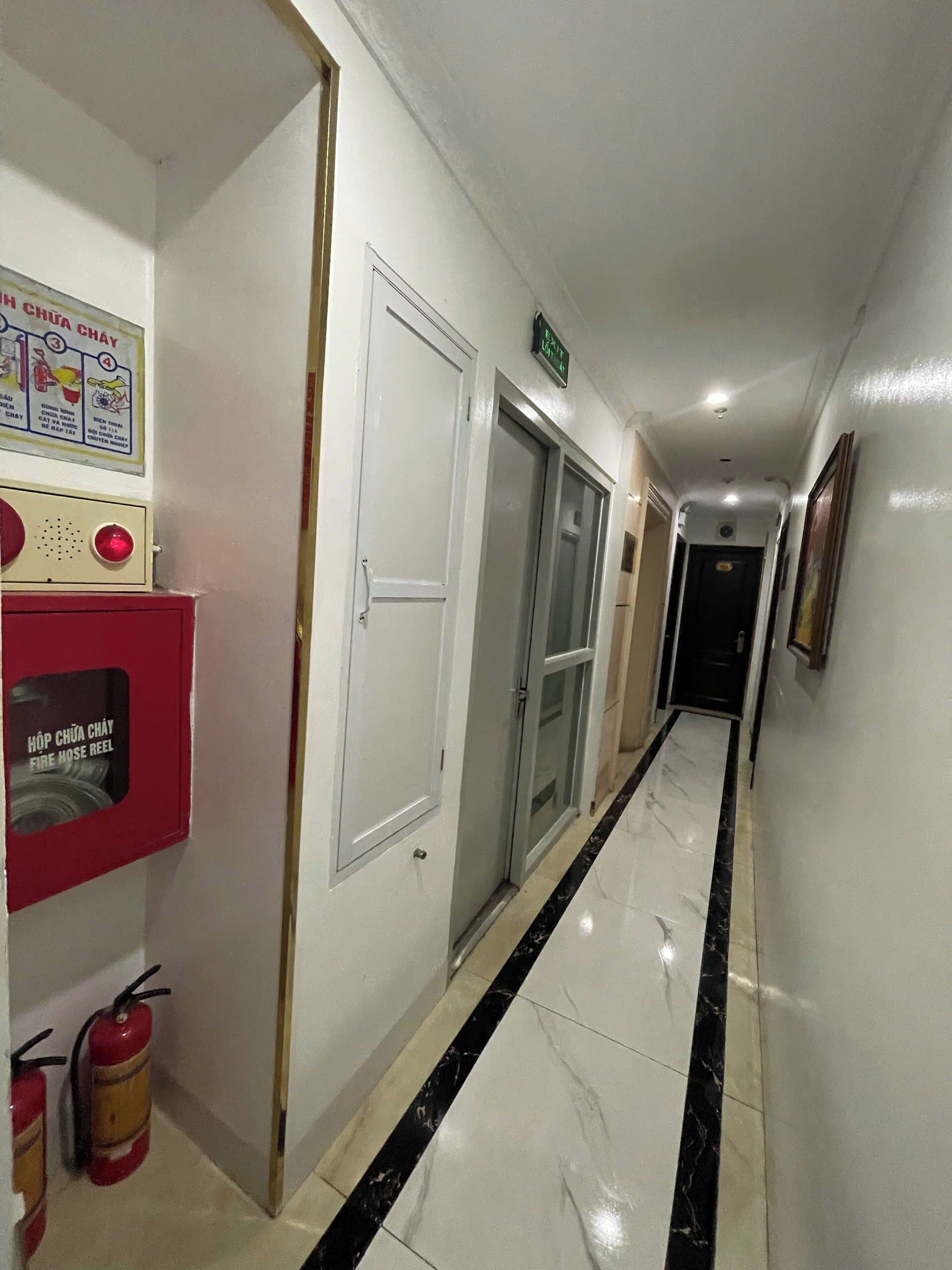 A hallway with a fire hose reel, a fire extinguisher, and a sign indicating the location of the fire hose reel.