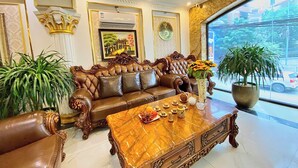 A luxurious living room with a brown leather sofa, a marble coffee table, and large potted plants. - Nam Cuong X Hotel (Hanoi)