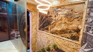 A lobby with a marble wall, a large circular artwork, and a modern light fixture. - Nam Cuong X Hotel (Hanoi)